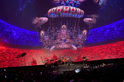 A live band performs on stage with colorful projections in the background.