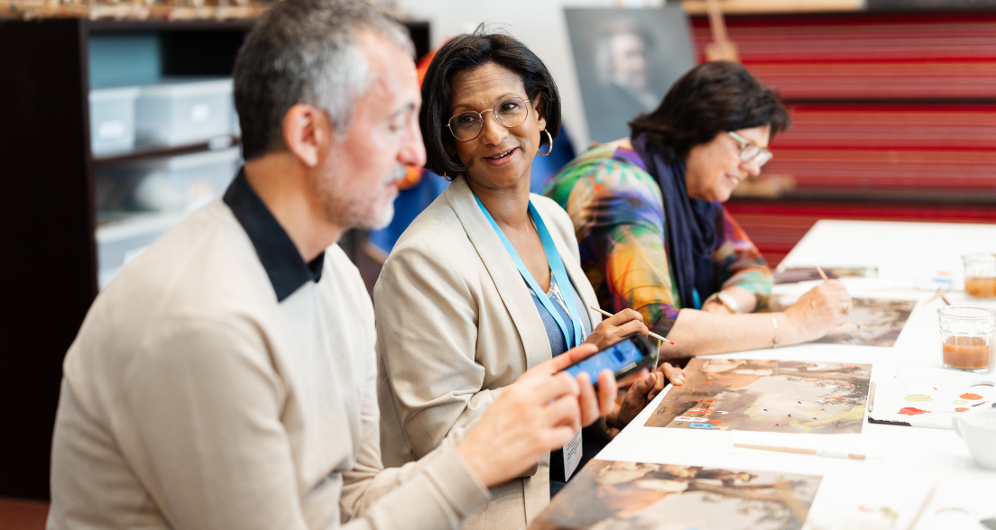 Three people enjoying a painting activity at a table.
