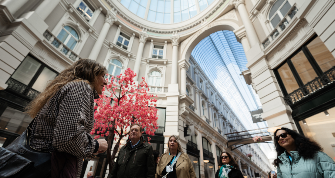 A group of people listening to a guide under a skylight.